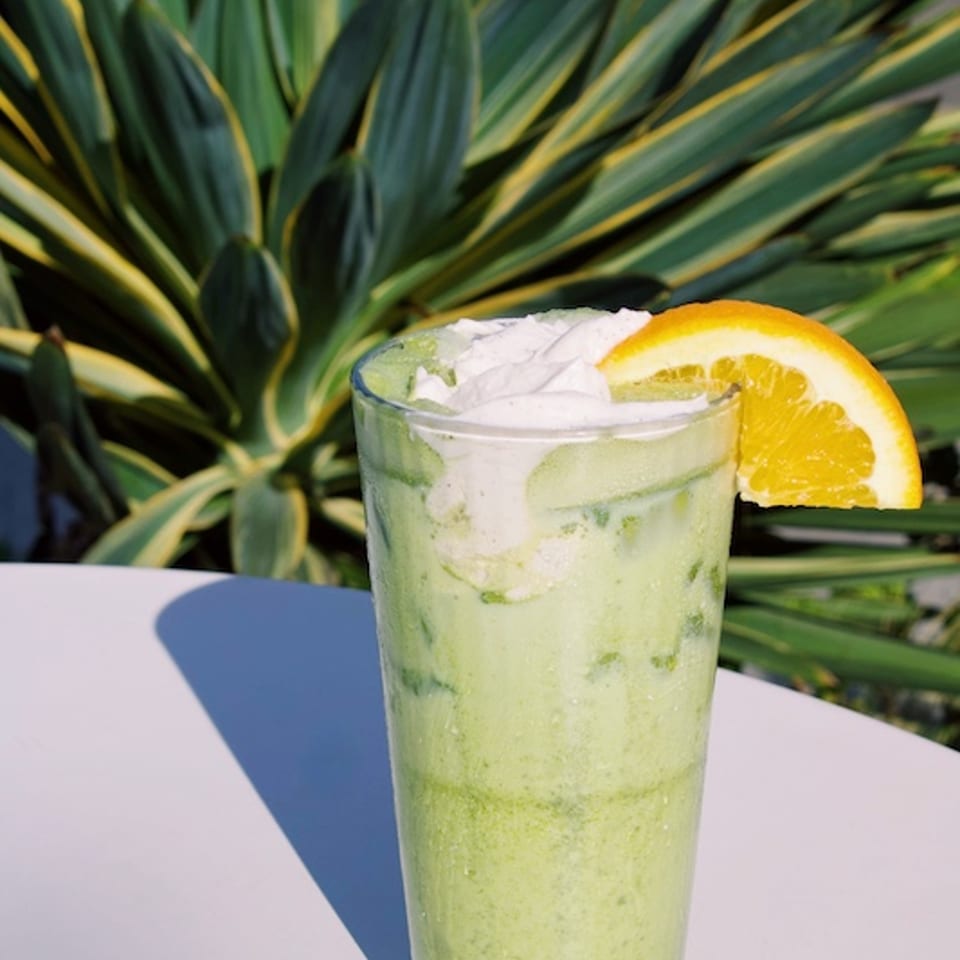 Sea Moss Sunrise Matcha with an orange slice outdoors.
