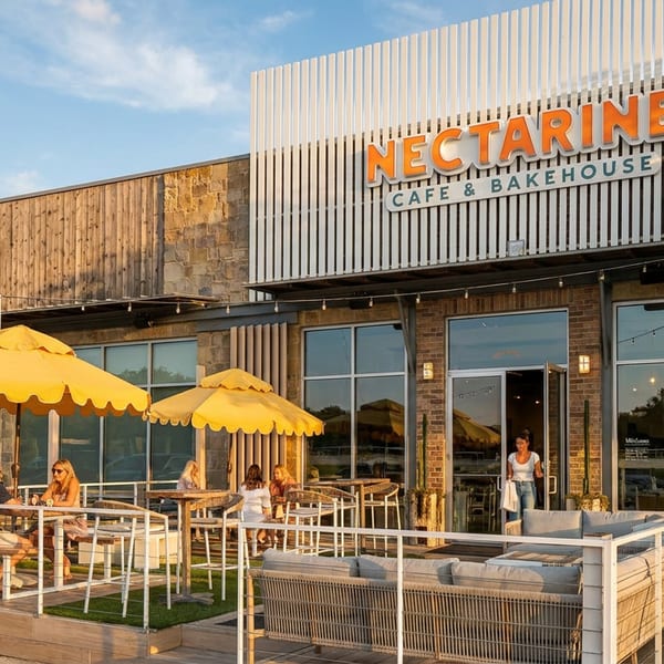 Nectarine Cafe & Bakehouse exterior with people dining on the outdoor patio under yellow umbrellas.