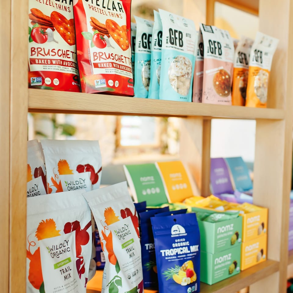 Packaged snacks displayed on wooden market shelves.